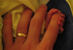 Holding the baby's hand. Can you tell whose is whose?
